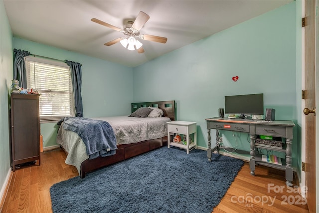 bedroom featuring ceiling fan, baseboards, and wood finished floors