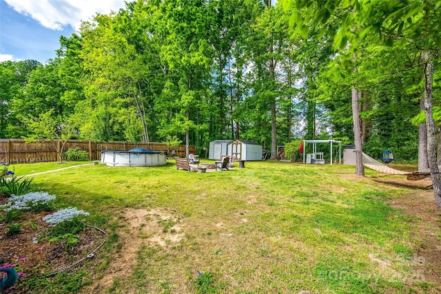 view of yard with a fenced in pool, a fenced backyard, a storage unit, and an outbuilding
