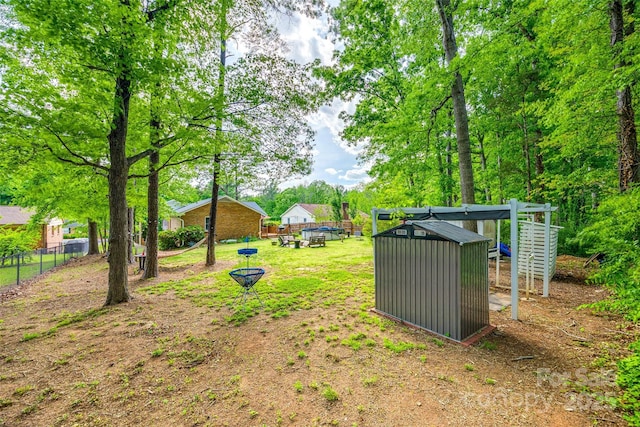 view of yard with fence, an outbuilding, and a storage unit