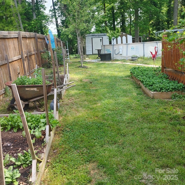 view of yard featuring fence, a vegetable garden, an outdoor structure, and a storage shed