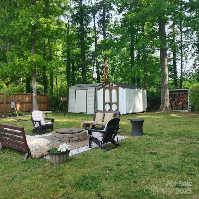 view of yard with a storage unit, an outbuilding, an outdoor fire pit, and fence