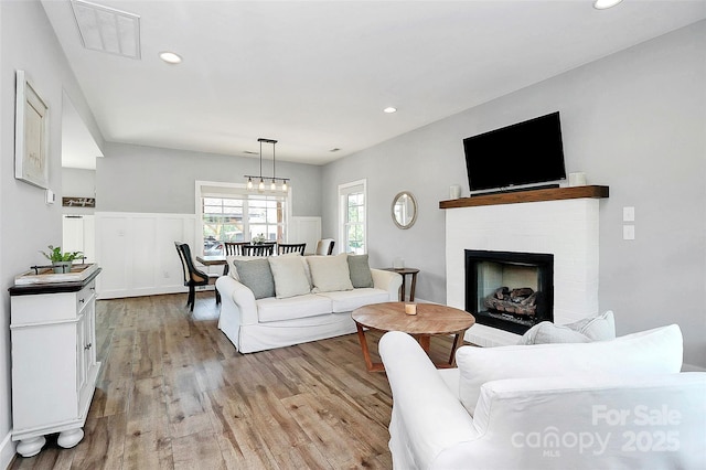 living area featuring a fireplace, recessed lighting, visible vents, and light wood-type flooring