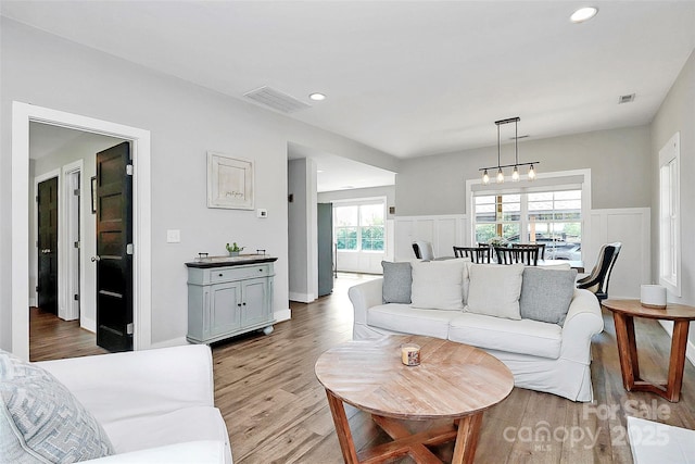 living area with a decorative wall, light wood-style floors, a wainscoted wall, recessed lighting, and visible vents