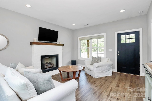 living room with visible vents, wood finished floors, a fireplace, baseboards, and recessed lighting
