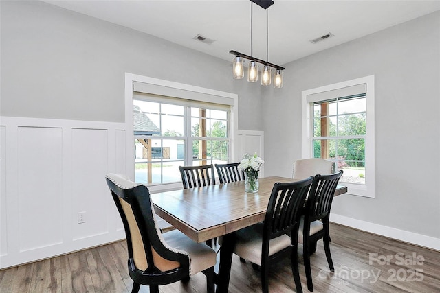 dining space featuring wainscoting, wood finished floors, and visible vents