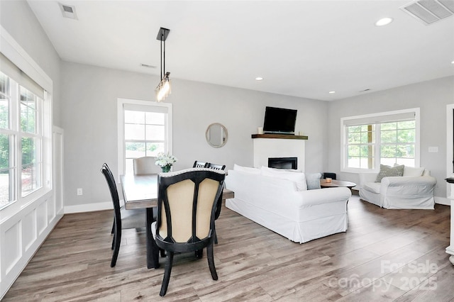 dining room with a glass covered fireplace, recessed lighting, wood finished floors, and visible vents