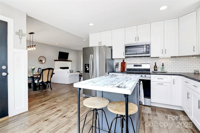 kitchen featuring decorative backsplash, stainless steel appliances, light wood-type flooring, and white cabinetry