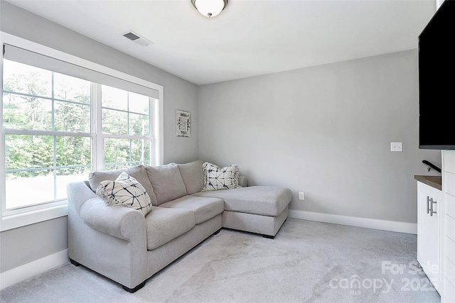 living area with light colored carpet, baseboards, and visible vents