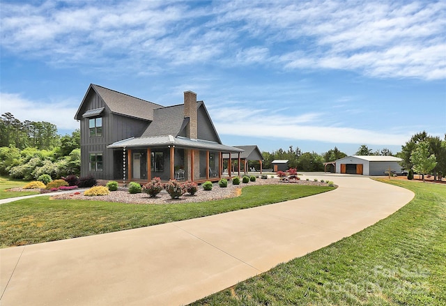 view of property exterior with a lawn, curved driveway, an outbuilding, and a chimney