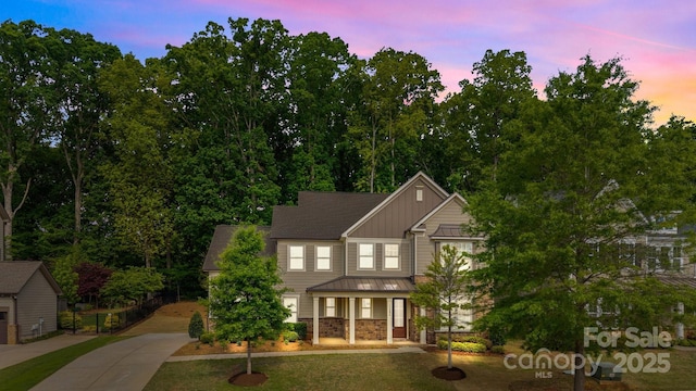 craftsman-style house with a standing seam roof, metal roof, covered porch, concrete driveway, and board and batten siding