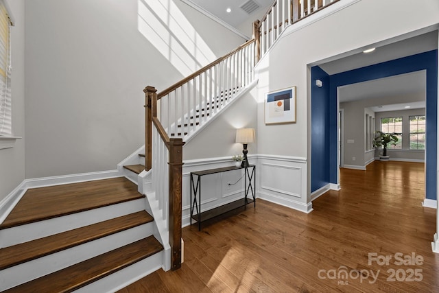 stairs with baseboards, wood finished floors, and visible vents
