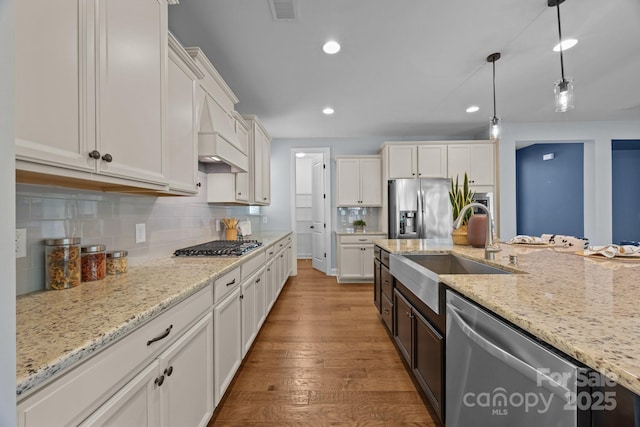 kitchen with visible vents, a sink, appliances with stainless steel finishes, hardwood / wood-style flooring, and white cabinetry