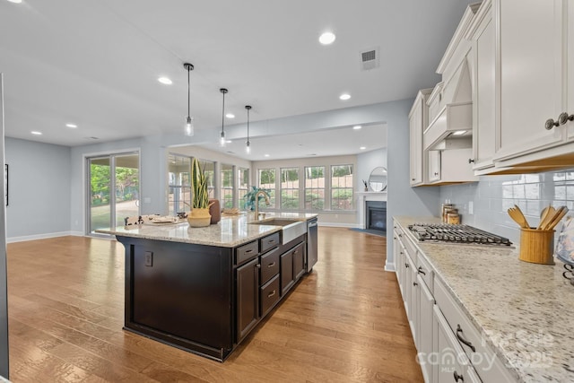 kitchen with visible vents, a sink, baseboards, appliances with stainless steel finishes, and open floor plan