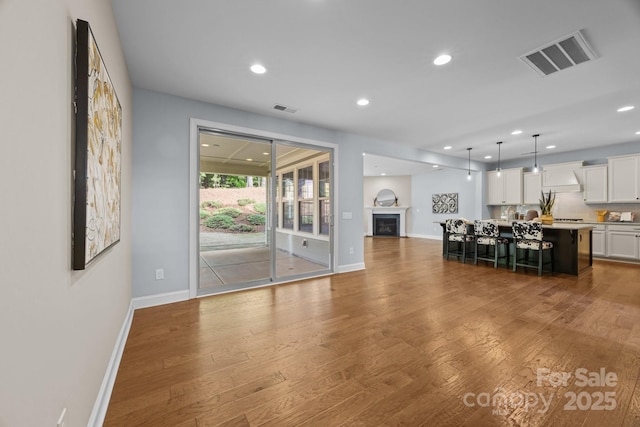 living room with baseboards, wood finished floors, visible vents, and recessed lighting