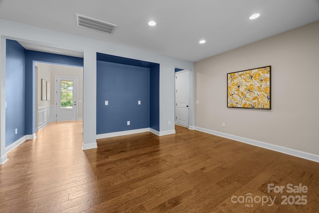 spare room with baseboards, wood finished floors, visible vents, and recessed lighting