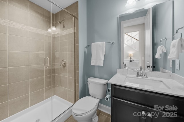 full bathroom featuring tile patterned floors, toilet, a stall shower, baseboards, and vanity