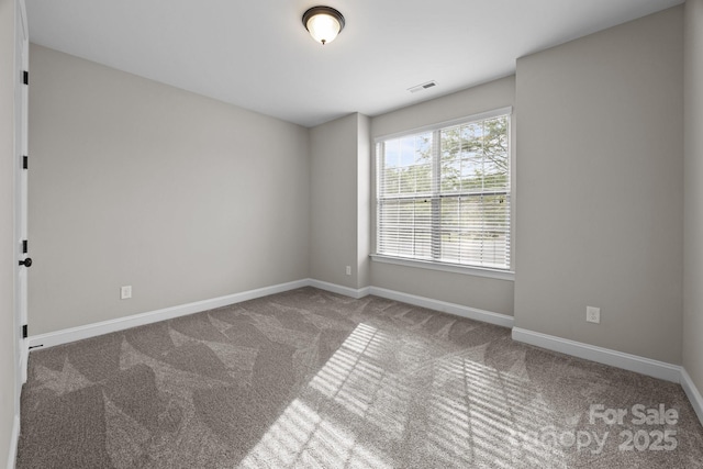spare room with baseboards, visible vents, and carpet