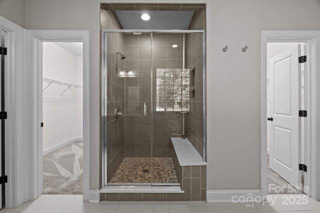 full bath with a shower stall, baseboards, and a spacious closet