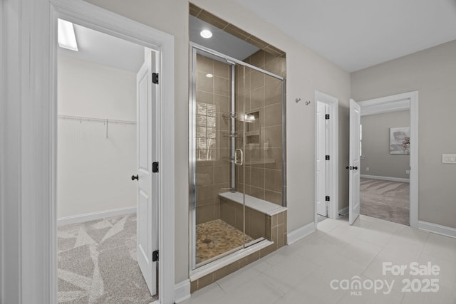 full bath featuring a shower stall, baseboards, and a walk in closet