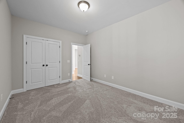 unfurnished bedroom with a closet, carpet flooring, and baseboards