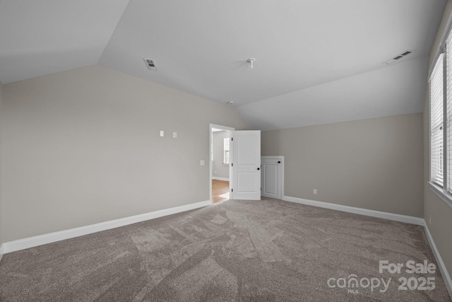 additional living space with lofted ceiling, baseboards, visible vents, and carpet