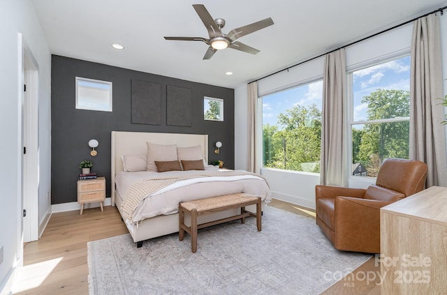 bedroom featuring light wood-type flooring, baseboards, and multiple windows