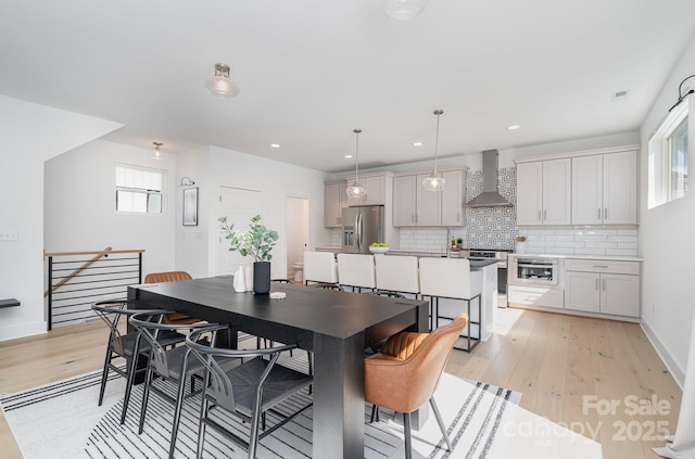 dining room with recessed lighting, light wood-style flooring, and baseboards