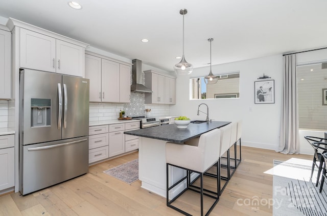 kitchen with range with electric stovetop, light wood-style floors, wall chimney exhaust hood, stainless steel fridge with ice dispenser, and a sink