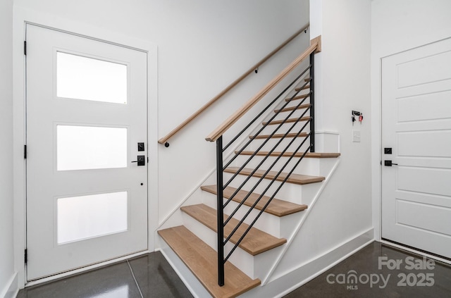 foyer with baseboards and stairway