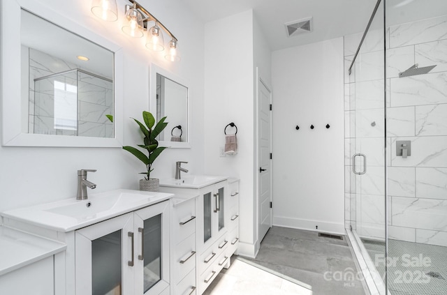 bathroom with visible vents, a shower stall, two vanities, a sink, and baseboards