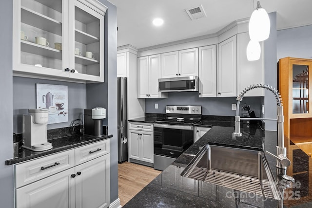 kitchen with a sink, glass insert cabinets, appliances with stainless steel finishes, white cabinetry, and visible vents
