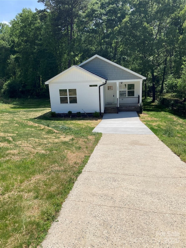 view of front of house with driveway, a front lawn, and covered porch