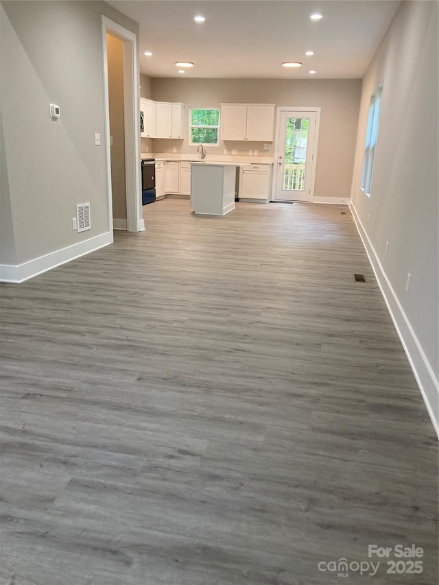 unfurnished living room featuring baseboards, wood finished floors, visible vents, and recessed lighting