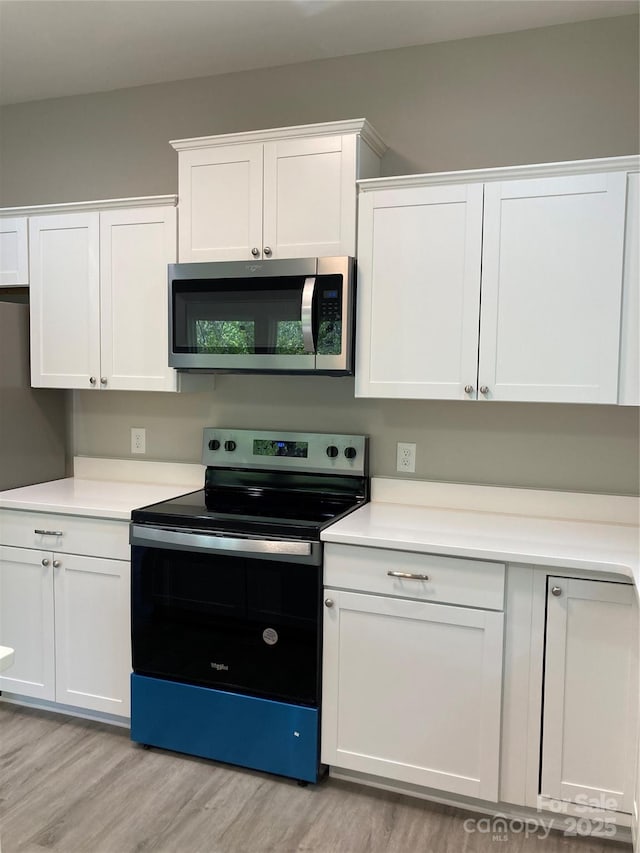 kitchen with light countertops, light wood-style floors, appliances with stainless steel finishes, and white cabinets