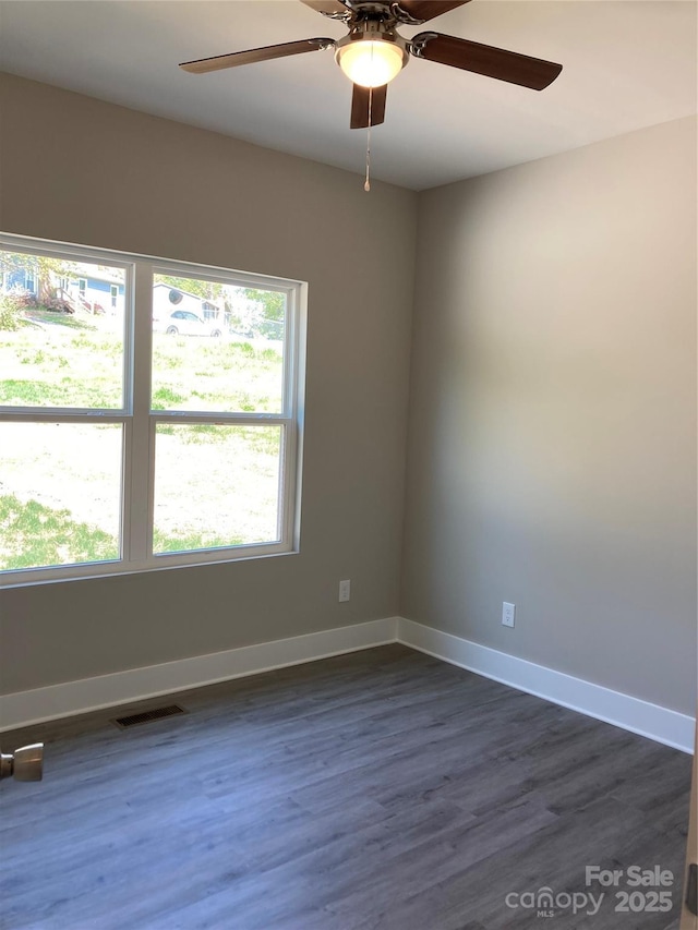 empty room featuring baseboards, a ceiling fan, dark wood-style flooring, and visible vents