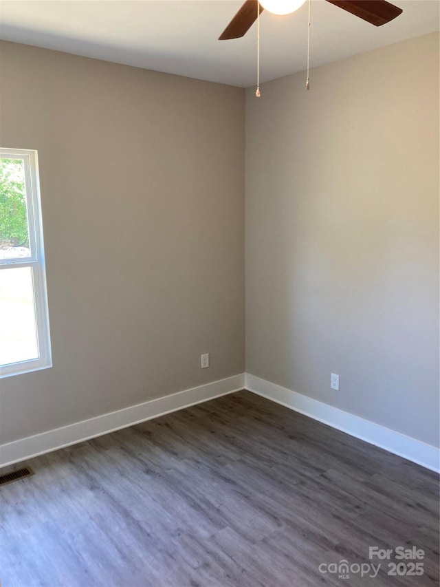 spare room featuring ceiling fan, baseboards, dark wood-style flooring, and visible vents