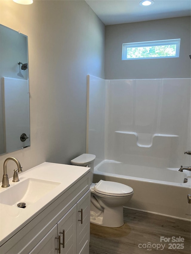 full bath with recessed lighting, wood finished floors, shower / bath combination, toilet, and vanity
