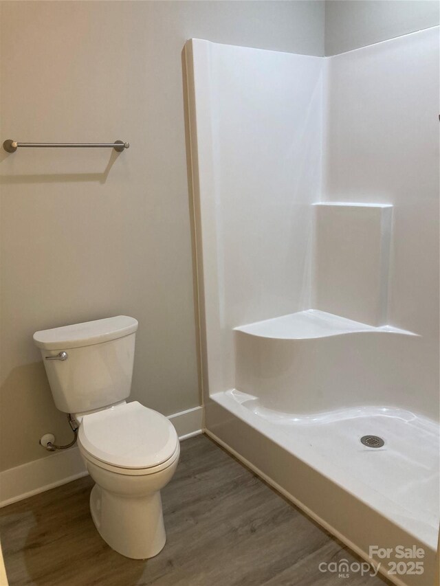 full bath featuring baseboards, walk in shower, wood finished floors, and toilet