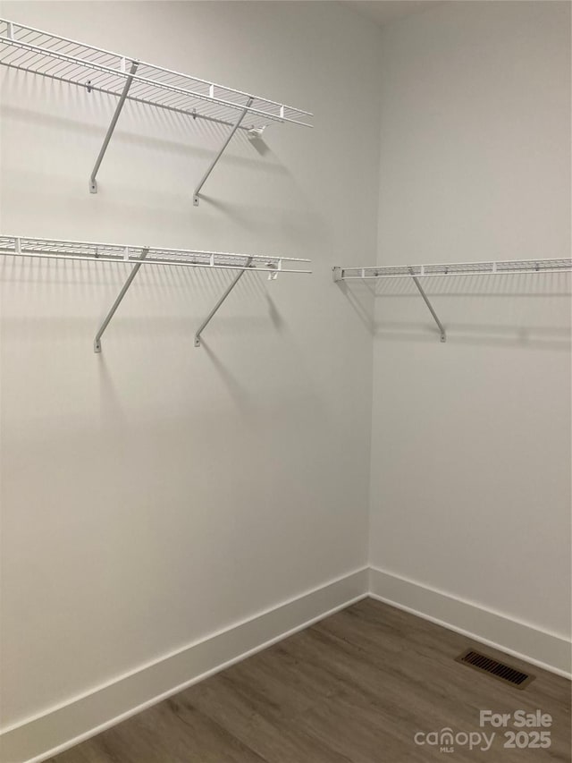 walk in closet featuring visible vents and dark wood finished floors