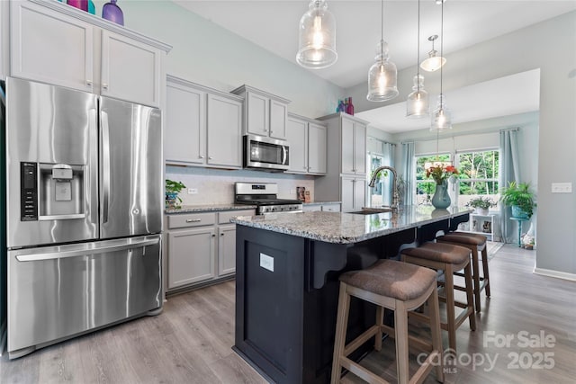 2124 Katie Alice Cir, Waxhaw, NC 28173 - kitchen featuring appliances with stainless steel finishes, a sink, light wood-style flooring, a kitchen bar, and light stone counters