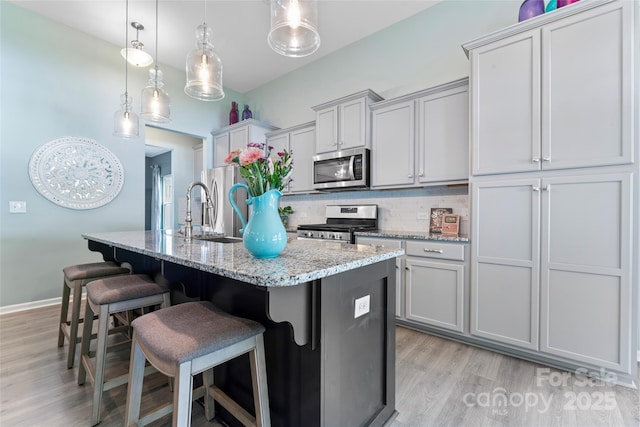 2124 Katie Alice Cir, Waxhaw, NC 28173 - kitchen with appliances with stainless steel finishes, a sink, a center island with sink, tasteful backsplash, and light wood finished floors