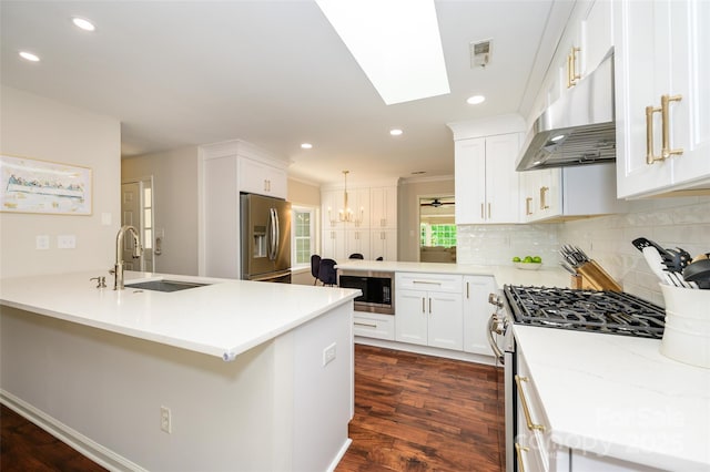 5916 Rexwood Pl, Charlotte, NC 28210 - kitchen with under cabinet range hood, visible vents, a sink, a peninsula, and appliances with stainless steel finishes