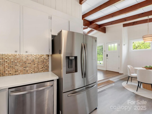 kitchen featuring stainless steel appliances, light countertops, a wealth of natural light, and tasteful backsplash