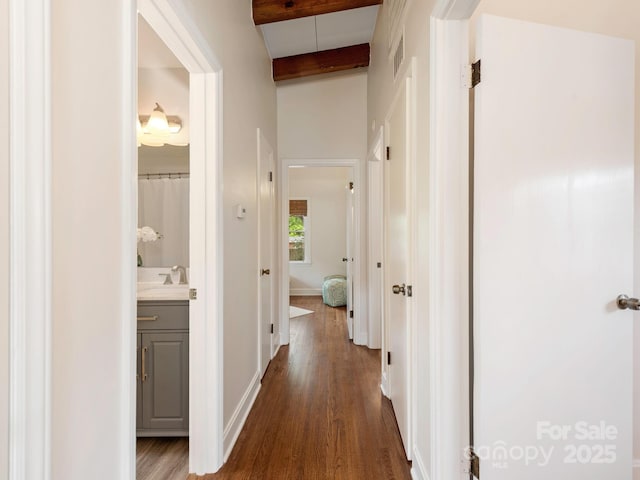 hallway featuring baseboards, visible vents, beam ceiling, and dark wood-style flooring