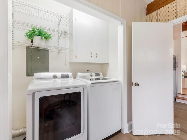 laundry area featuring electric panel, independent washer and dryer, light wood-style floors, and cabinet space