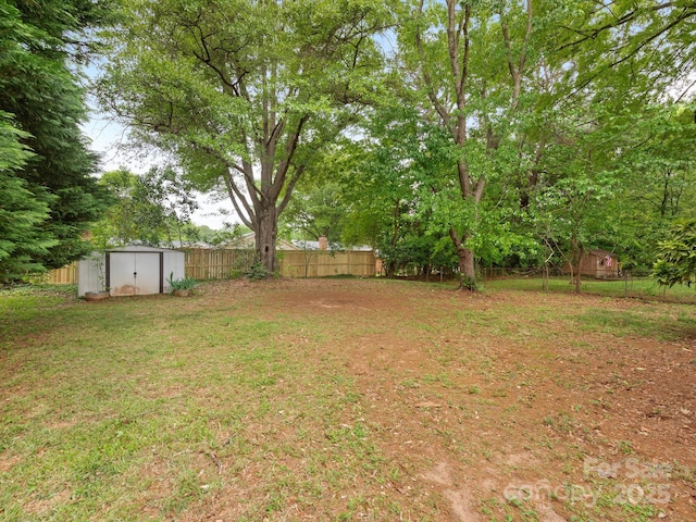 view of yard featuring a storage shed, an outbuilding, and fence