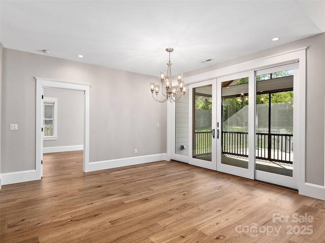 unfurnished dining area featuring a chandelier, french doors, baseboards, light wood-type flooring, and visible vents