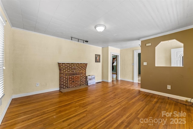 unfurnished living room featuring rail lighting, ornamental molding, baseboards, and hardwood / wood-style floors