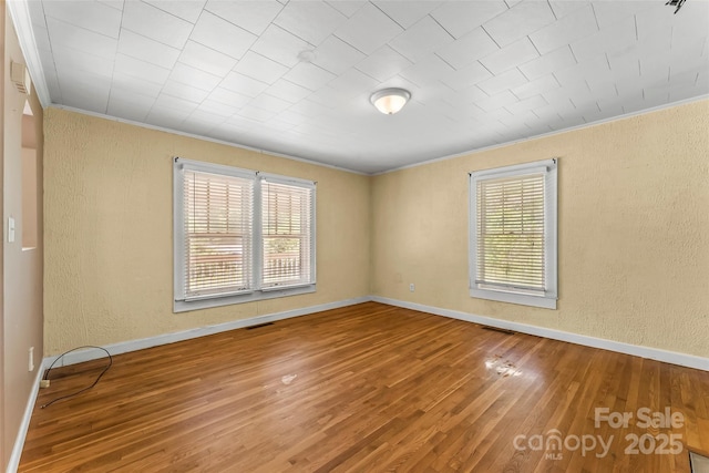 spare room featuring ornamental molding and a textured wall