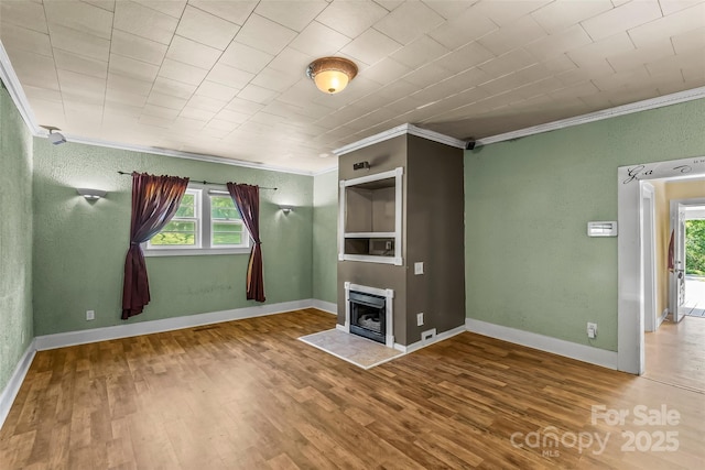 unfurnished living room featuring crown molding, baseboards, and wood finished floors